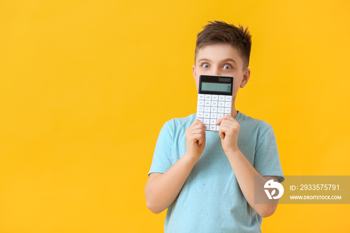Surprised little boy with calculator on color background