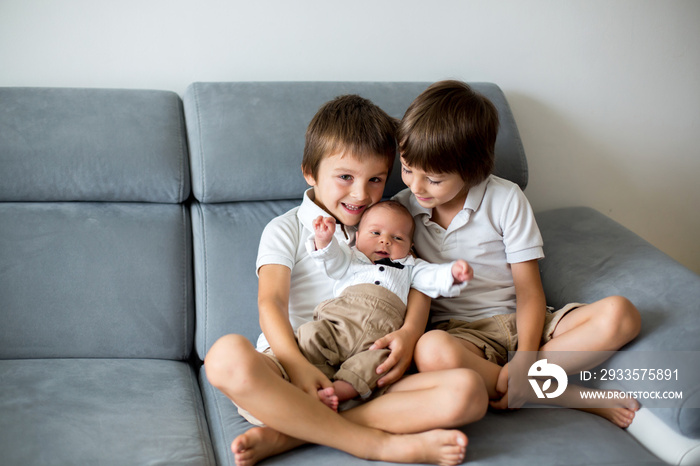 Sweet preschool boys, brothers, hugging with tenderness and care his little newborn brother