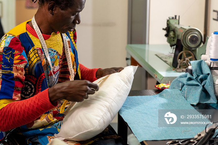 African textile industry artisan at work, tailor taking a measurement to create a pillow with wax fabrics typical of African culture, concept of small business and diversity