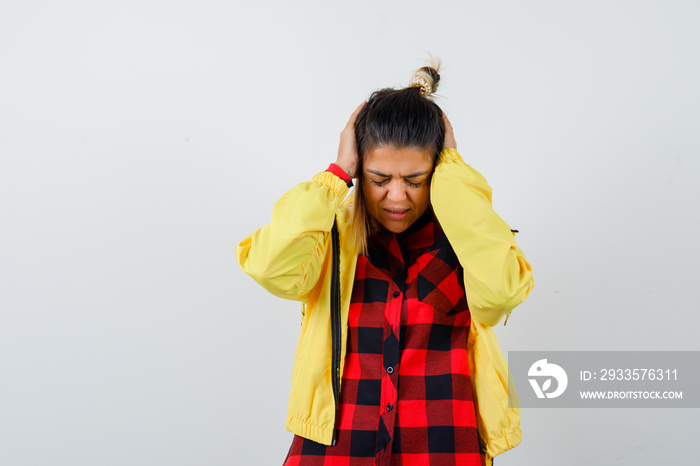 Portrait of cute woman holding hands on ears in shirt, jacket and looking annoyed front view