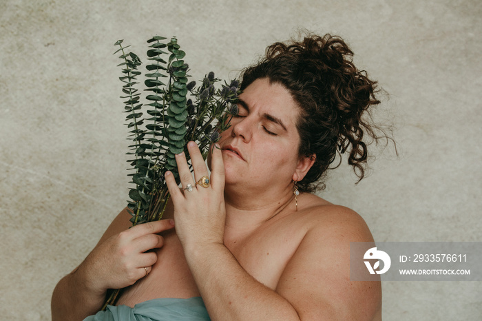 close up portrait of a plus size woman holding eucalyptus