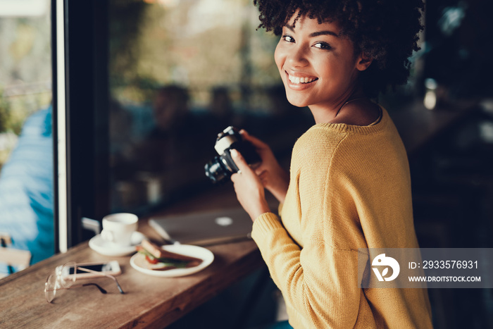 Cheerful lady holding her camera in hands