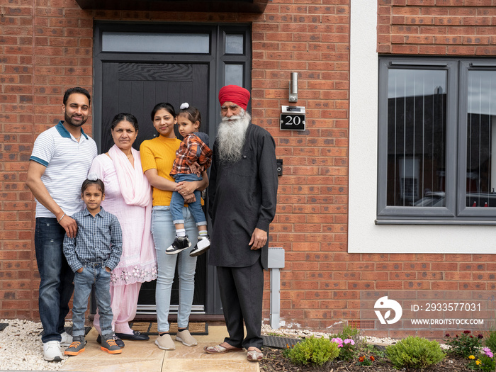 Portrait of multi-generation family (2-3,6-7) standing on front porch