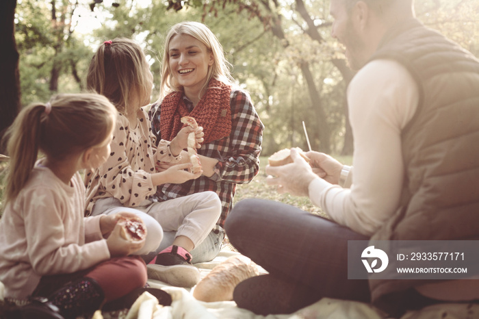 Cheerful family having picnic together in park.