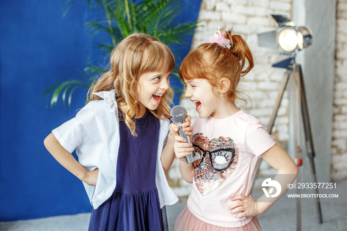 Two happy little children sing a song in karaoke. The concept is childhood, lifestyle, music, singing, friendship.