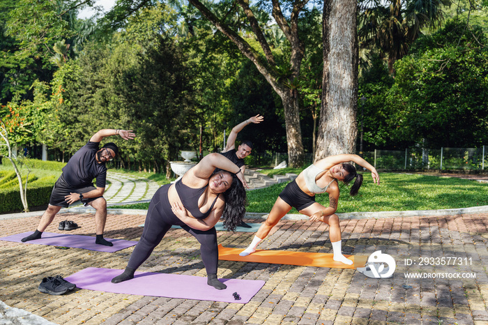 Group of friends doing yoga in the park together