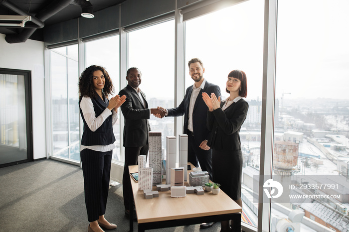 Business partnership meeting concept. Multiethnic businesspeople, real estate, agents, developers, handshake after successful deal of city district urban planning project, good team work.