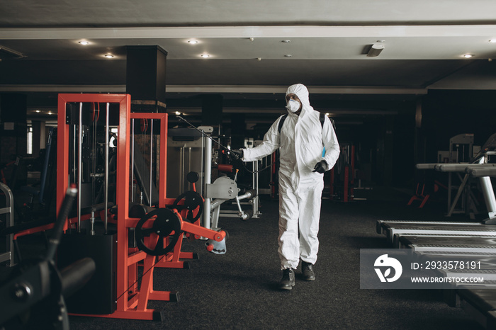 Cleaning and Disinfection in crowded places amid the coronavirus epidemic Gym cleaning and disinfection Infection prevention and control of epidemic. Protective suit and mask and spray bag