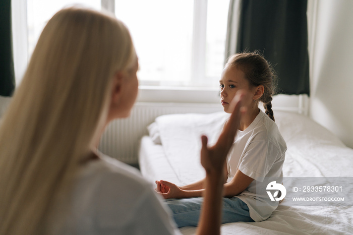 Closeup view from shoulder of unrecognizable angry young mother scolding, raising voice, scream and gesturing with hands at stubborn difficult little child daughter at home. Concept of family problems