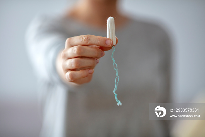 Close up of a woman’s hands which are holding a tampon. Tampo on womans hand before intravaginal aplication. Woman holds a tampon in toilet. Woman holds a tampon sitting in a toilet