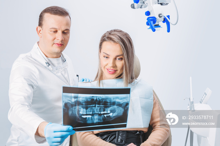 The doctor shows a x-ray picture to patient. Closeup. Doctor hands in gloves hold x-ray picture of patient’s jaw.