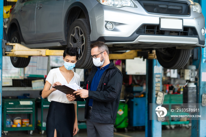 Mechanic man and woman customer wearing medical face mask protection coronavirus and check the car condition before delivery.