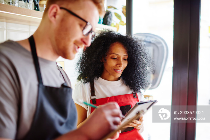 Confident waiter taking order working with partner in coffee shop