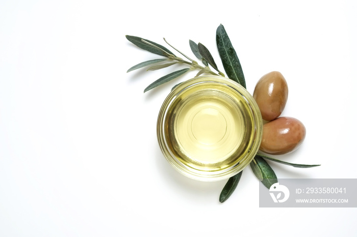 Bunch of local produce Turkish green gemlik olives with glass cup of extra virgin golden oil and olea europaea tree leaves. Close up, top view, copy space, isolated white background.