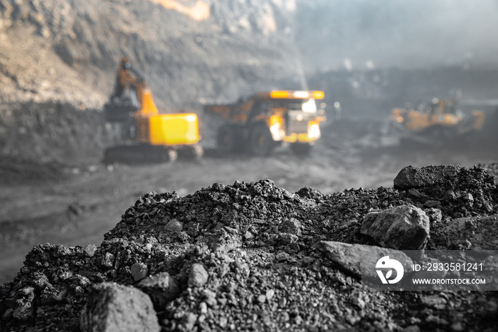 Coal open pit mine. In background blurred loading anthracite minerals excavator into large yellow truck