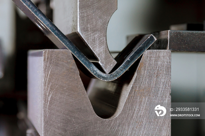 Bending sheet metal on a hydraulic machine at the factory. Bend tools, press brake punch and die. Close-up.