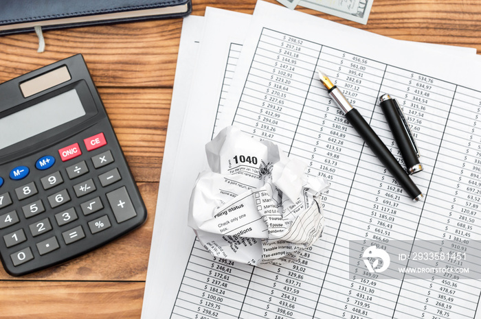 Crumpled tax form with financial documents, calculator and notepad on the table. Top view. Business concept.