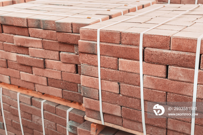 pallets and packages of freshly produced red bricks in a construction warehouse on the street. Concept of repair and building materials