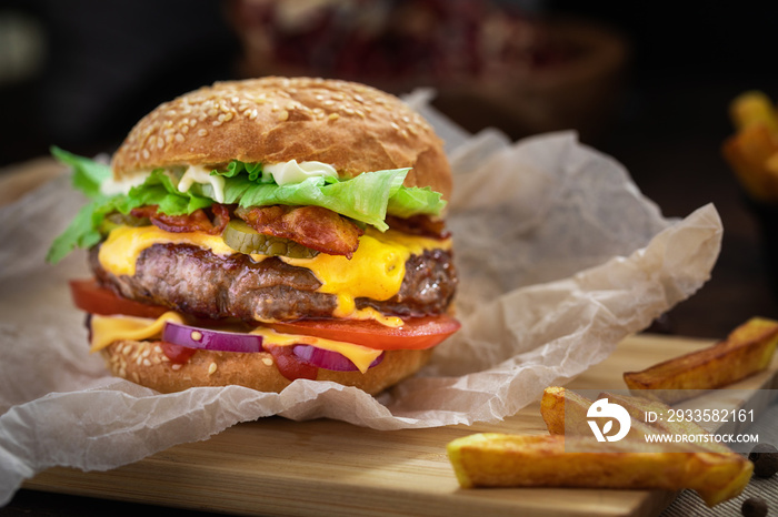 Tasty grilled beef burger served on craft paper on a rustic wooden table with French fries