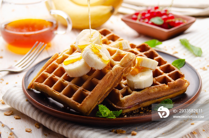 Homemade crispy Belgian waffles served with banana and honey