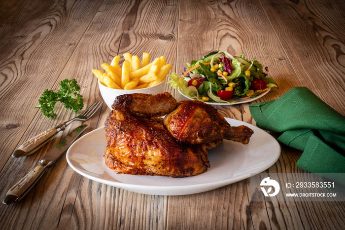 Brathänchen auf Teller mit Salata und Pommes Frites