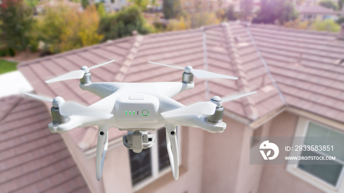 Unmanned Aircraft System (UAV) Quadcopter Drone In The Air Over House Inspecting the Roof