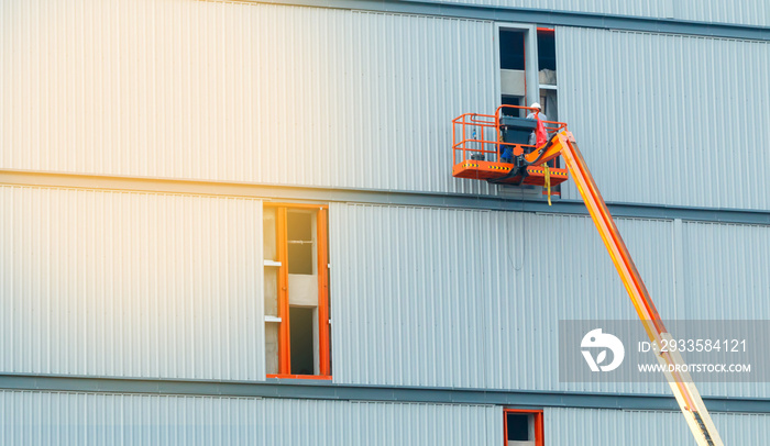 construction worker at construction site using lifting boom machinery