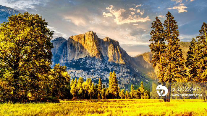 Setting Sun casting glowing sunlight over the almost dry Yosemite Upper Falls at Yosemite Point, the southern shoulder of the Half Dome granite rock in Yosemite National Park, California, USA