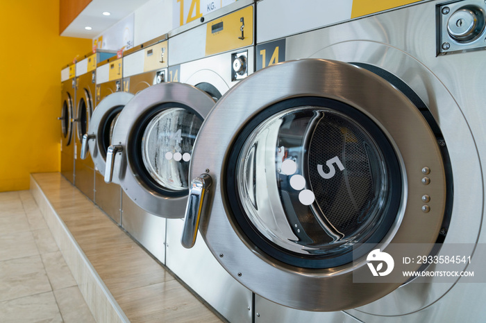 A row of qualified coin-operated washing machines in a public store. Concept of a self service commercial laundry and drying machine in a public room.