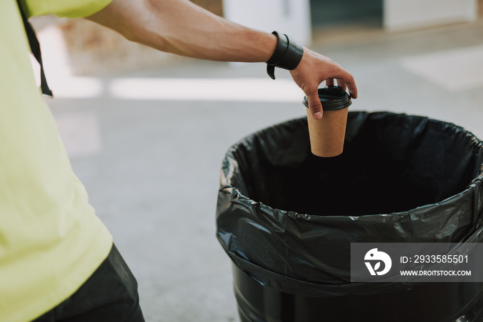 Man throwing paper cup into rubbish bin