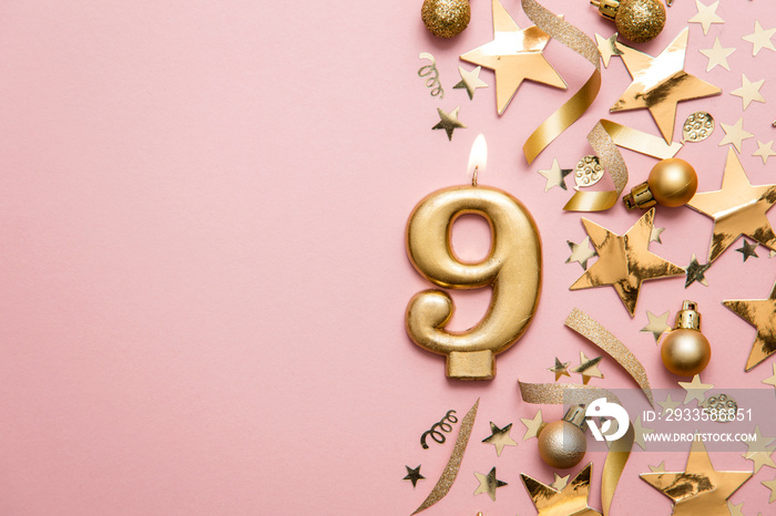 Number 9 gold celebration candle on star and glitter background