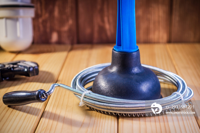 Clean plastic plunger with blue handle and cable on wooden background