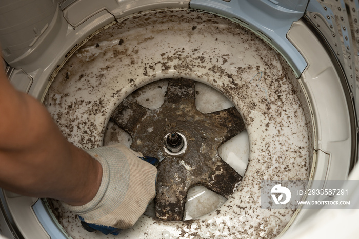 man taking apart a dirty washing machine