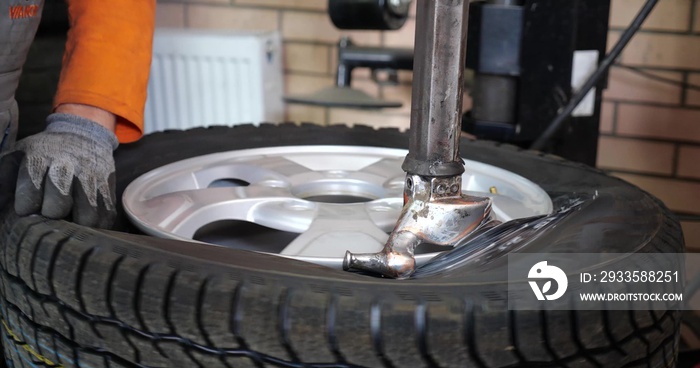 Tire service Man put on tyre on car wheel by special tool