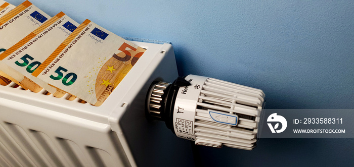 A heating radiator battery with a temperature controller from which 50 euro bills stick out. The concept of high heating costs. Rise in energy prices, energy crisis and recession