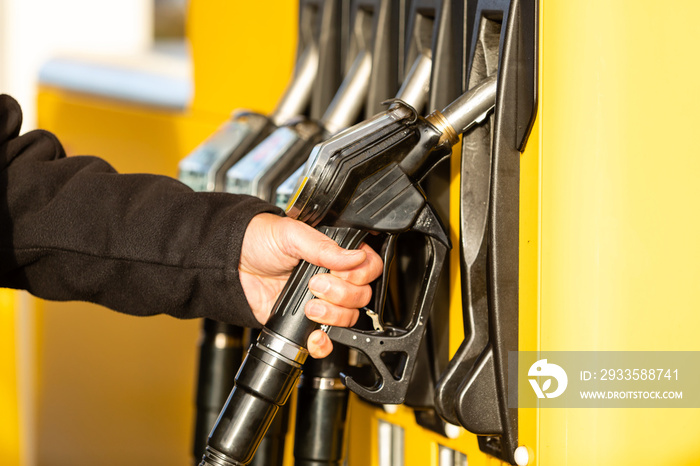 Hand with fuel nozzle at a gas station