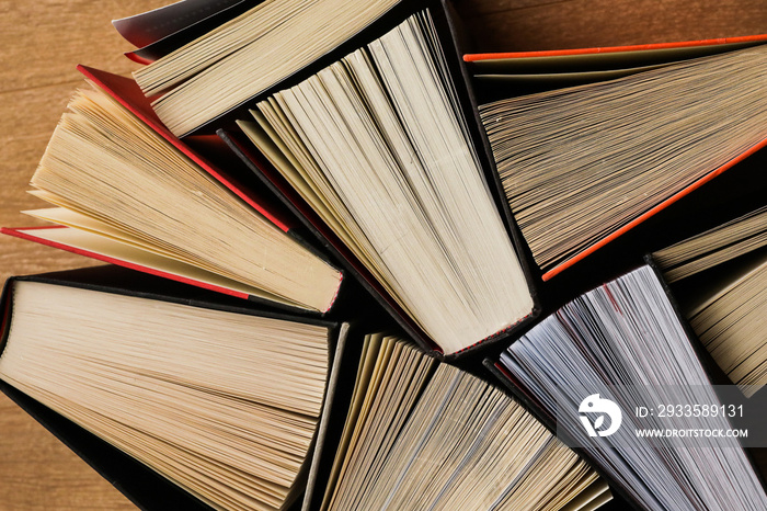 Colourful thick open books stand on a wooden background