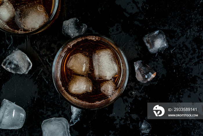 Alcohol whiskey cocktail with cola and ice. On the black table.copy space. top view