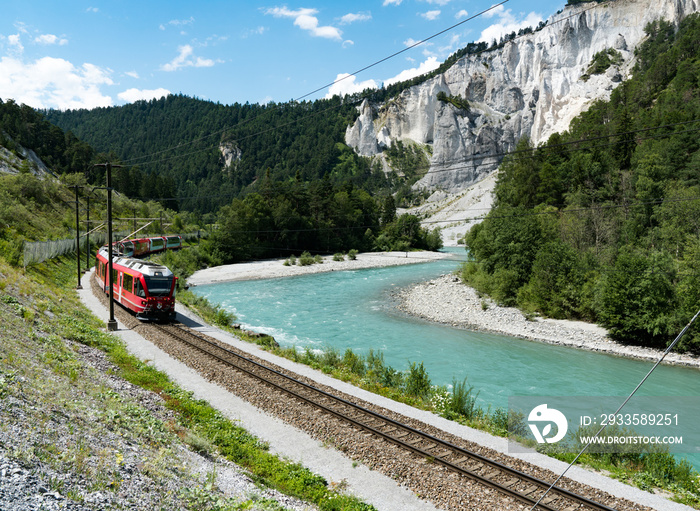 the Rhaetian railway train on the banks of the Rhine River in the Ruinaulta Gorge