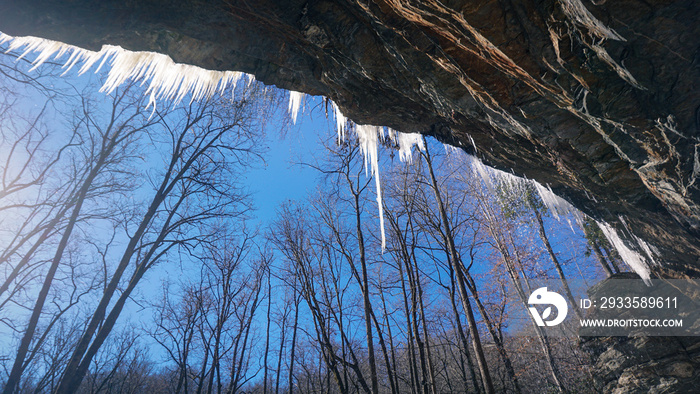 A scenic winter view of icicles hanging over Moore Cove Falls in Pisgah National Forest, North Carolina.