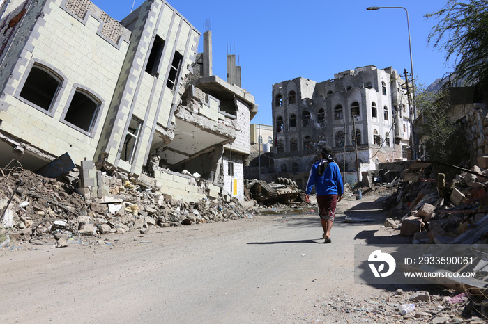 A Yemeni walks on the rubble of destroyed houses due to war and fierce fighting in Taiz city