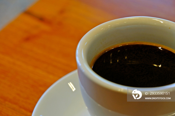 A cup of hot black coffee, hot Americano coffee on the blurred wooden table. Selective focus.