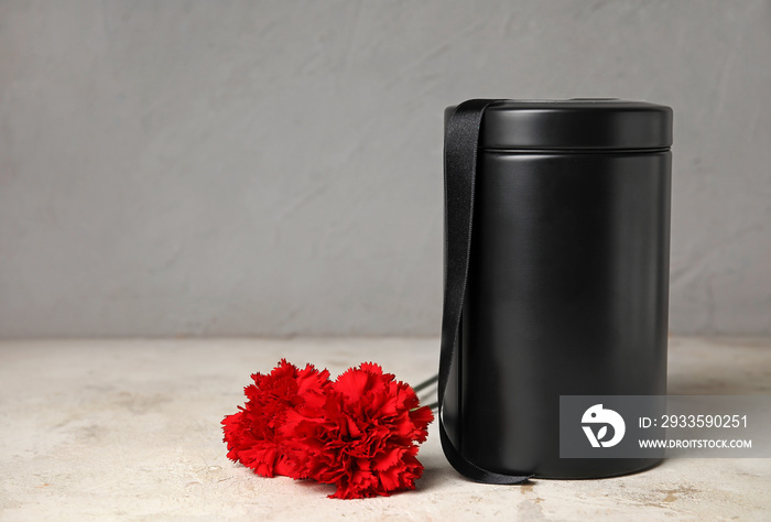 Mortuary urn with carnation flowers on light background