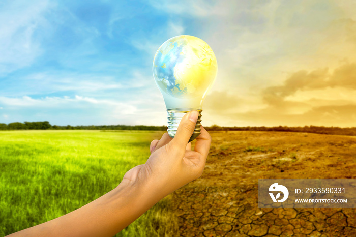 Human hands holding earth inside the light bulb