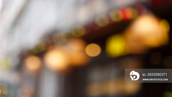 Blur background of European city street with bokeh of garlands, shop windows, cafe signboards