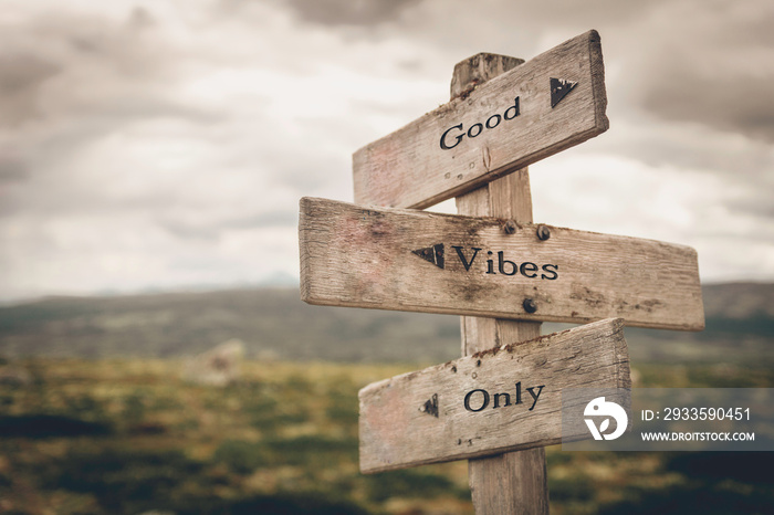 Good vibes only text on wooden rustic signpost outdoors in nature/mountain scenery. Mental and positive concept.