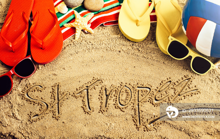 Summer concept of sandy beach, colorful thongs shoes, sunglasses, ball and inscription saint tropez