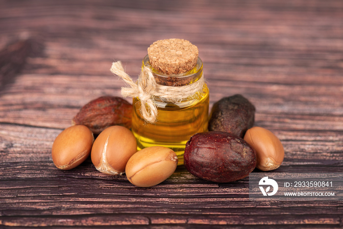 Argan oil, on wooden background. Argan nuts and seeds, for cosmetic and beauty products. Natural argan fruit from Morocco.