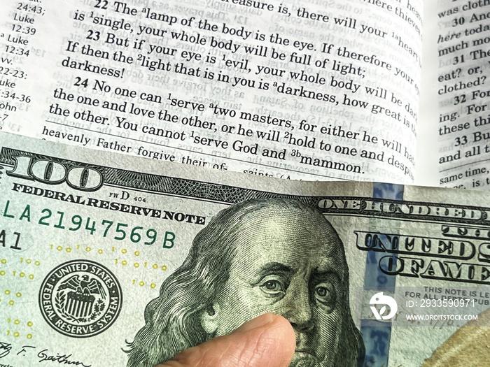 The Holy Bible in English with a tab from the $ 100 banknote showing a passage from the Gospel according to St. Matthew 6:24