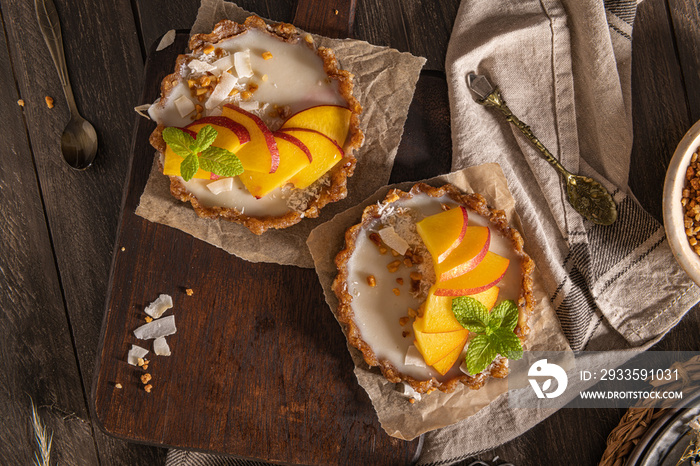 Nectarine vegan tarts with grated coconut and crunchy peanuts. Date, walnut, almond and hazelnut base.